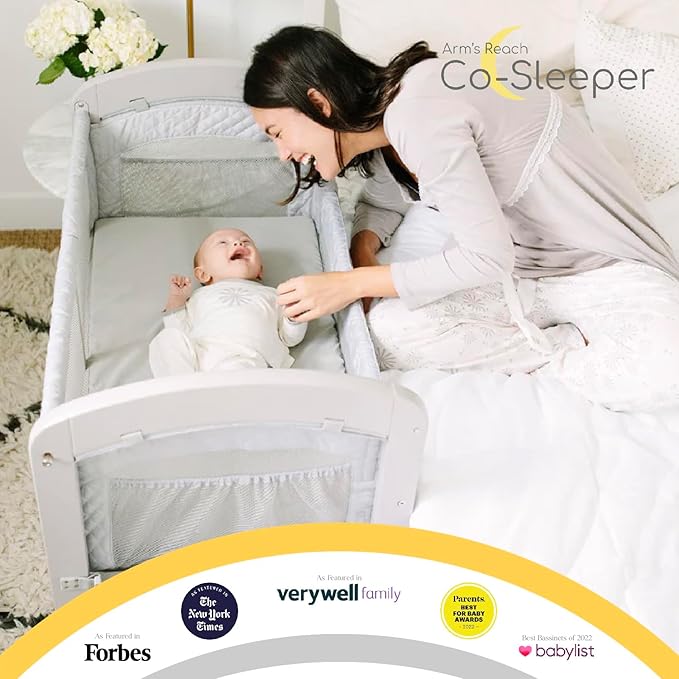 Arm’s Reach Cambria Co-Sleeper Bedside Bassinet Featuring Height-Adjustable Legs, Curved Wooden Ends, Breathable Mesh Sides with Pockets, and Large Lower Storage Basket, White